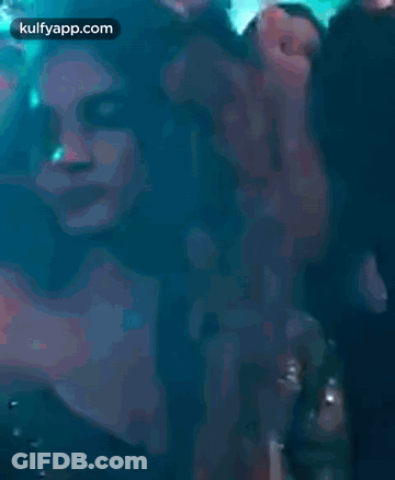A Woman Is Dancing In A Club With Her Hands In The Air And Smiling . GIF
