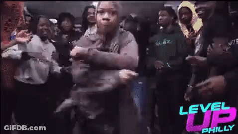 A Woman Is Dancing In A Crowd Of People At A Party . GIF