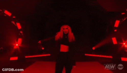 A Woman Is Dancing In A Dark Room With Red Lights . GIF