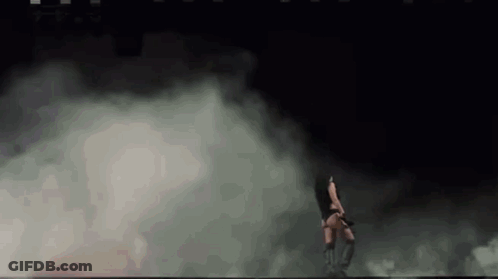 A Woman Is Dancing In A Dark Room With Smoke Coming Out Of The Walls . GIF