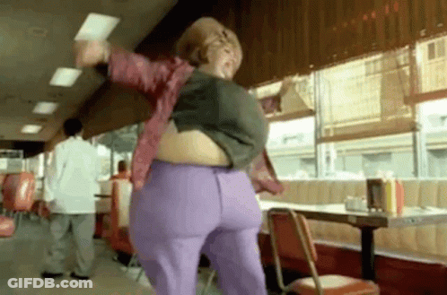 A Woman Is Dancing In A Diner With A Very Large Belly . GIF