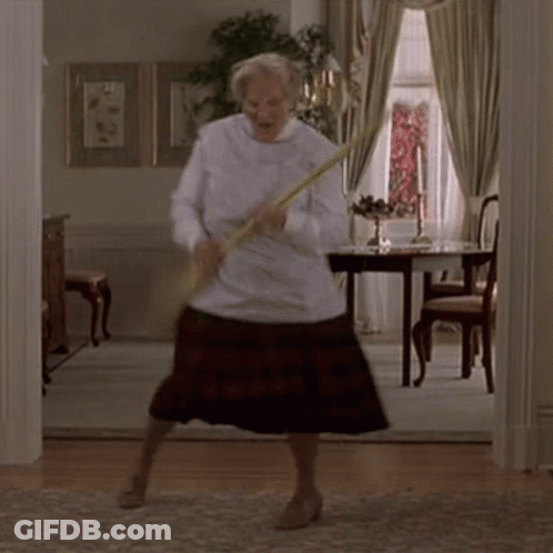 A Woman Is Dancing In A Living Room While Holding A Broom In Her Hand . GIF