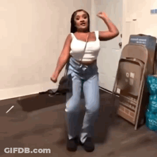 A Woman Is Dancing In A Room In Front Of Folding Chairs . GIF
