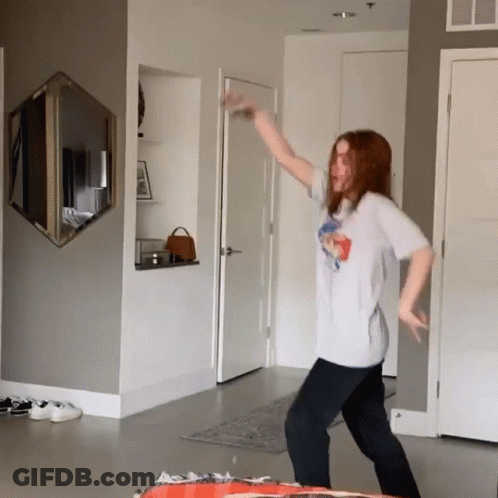 A Woman Is Dancing In A Room With A Mirror On The Wall GIF