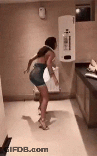 A Woman Is Dancing In A Room With A White Wall . GIF