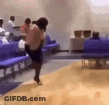A Woman Is Dancing In A Waiting Room In Front Of Purple Benches . GIF