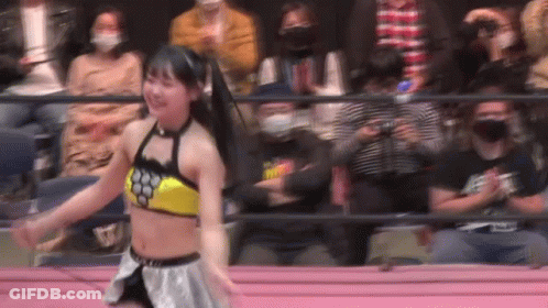 A Woman Is Dancing In A Wrestling Ring In Front Of A Crowd Of People . GIF