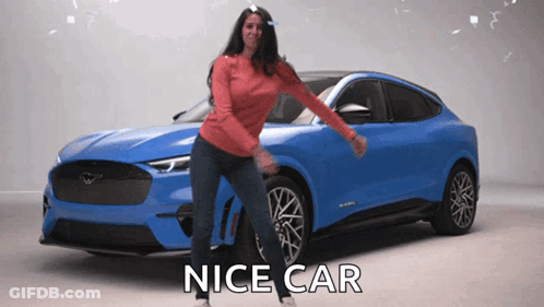 A Woman Is Dancing In Front Of A Blue Car That Says Nice Car On The Bottom GIF