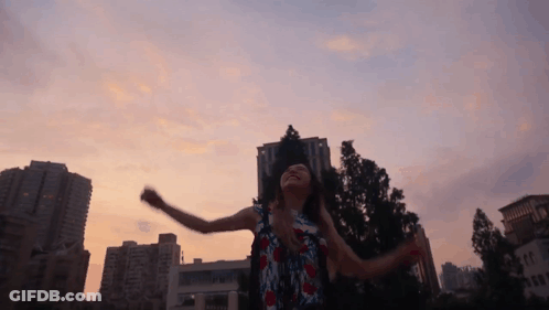 A Woman Is Dancing In Front Of A City Skyline GIF