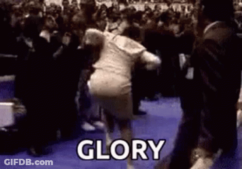 A Woman Is Dancing In Front Of A Crowd And The Word Glory Is Written On The Floor . GIF