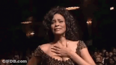 A Woman Is Dancing In Front Of A Crowd In A Dark Room . GIF