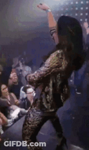 A Woman Is Dancing In Front Of A Crowd Of People At A Party . GIF