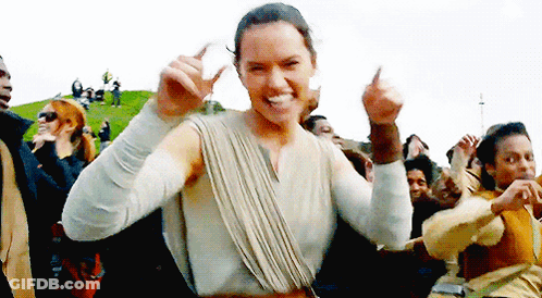 A Woman Is Dancing In Front Of A Crowd Of People While Giving A Thumbs Up . GIF