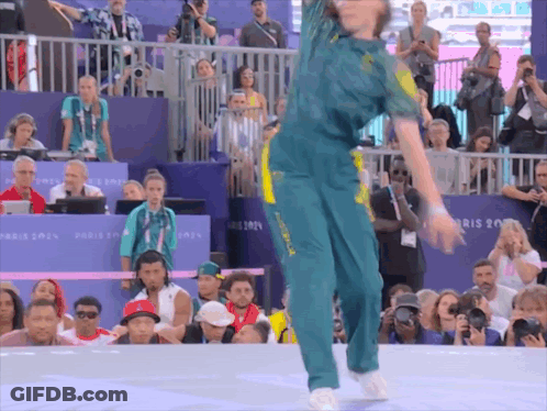 A Woman Is Dancing In Front Of A Crowd With A Sign That Says Paris 2014 GIF