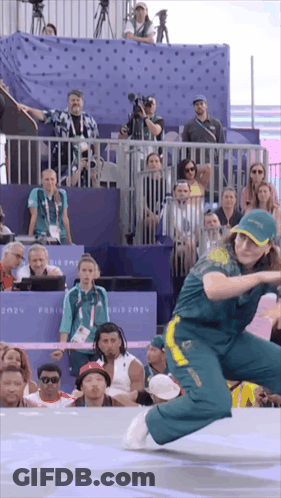A Woman Is Dancing In Front Of A Crowd With A Sign That Says Paris 2021 On It GIF