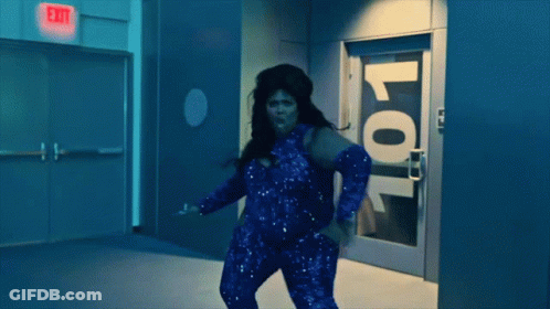 A Woman Is Dancing In Front Of A Door With The Number 101 On It GIF