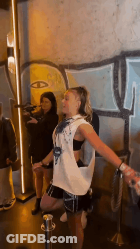 A Woman Is Dancing In Front Of A Graffiti Wall . GIF