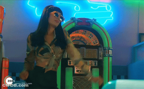 A Woman Is Dancing In Front Of A Jukebox That Says Zees On It GIF