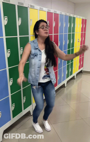 A Woman Is Dancing In Front Of A Row Of Lockers GIF