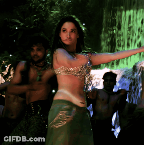 A Woman Is Dancing In Front Of A Waterfall In A Green Light GIF