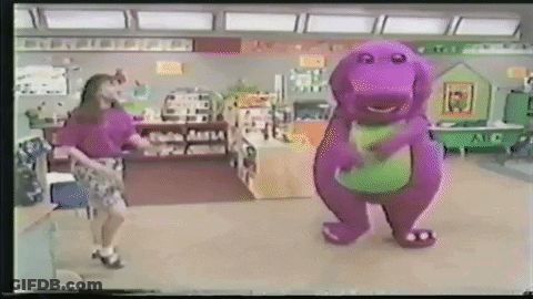 A Woman Is Dancing Next To A Purple Dinosaur In A Classroom . GIF
