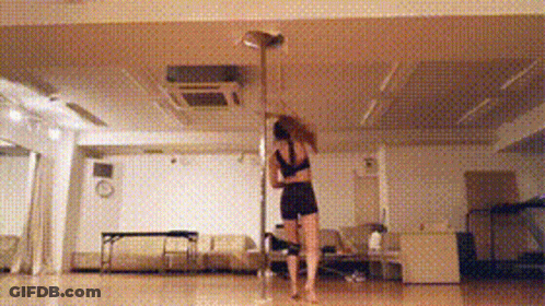A Woman Is Dancing On A Pole In A Room GIF