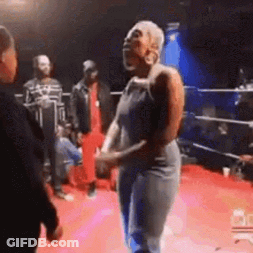A Woman Is Dancing On A Red Carpet In A Boxing Ring While A Man Talks To Her . GIF