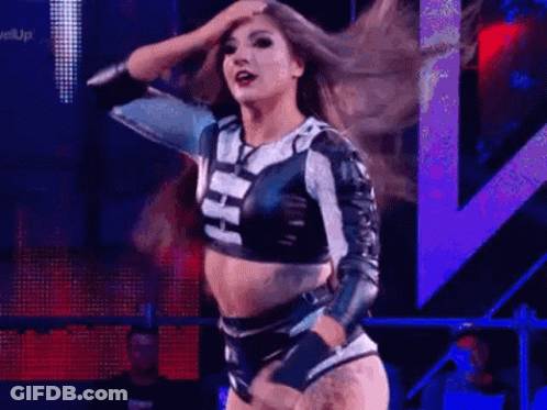 A Woman Is Dancing On A Stage In A Wrestling Ring . GIF