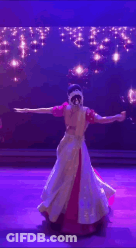 A Woman Is Dancing On A Stage In Front Of A Blue Background GIF