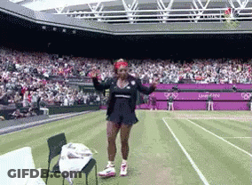 A Woman Is Dancing On A Tennis Court In Front Of A Large Crowd GIF