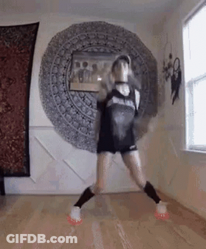 A Woman Is Dancing On A Wooden Floor In A Room With A Mandala On The Wall . GIF