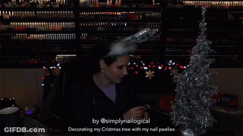 A Woman Is Decorating A Christmas Tree With Her Nail Peelies GIF