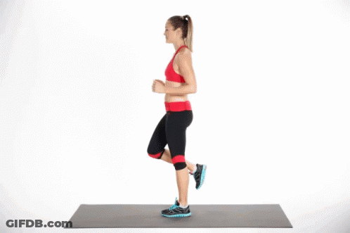 A Woman Is Doing A Workout On A Yoga Mat While Standing On One Leg . GIF