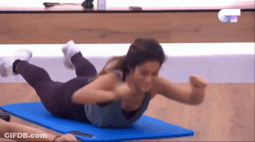 A Woman Is Doing Exercises On A Blue Mat On A TV Show GIF