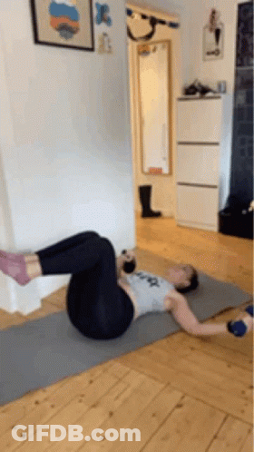 A Woman Is Doing Exercises On A Yoga Mat In A Room . GIF