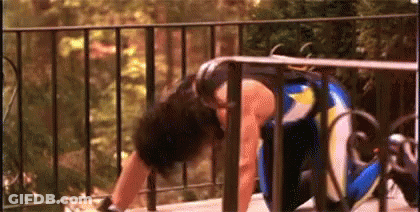 A Woman Is Doing Push Ups On A Balcony Next To A Fence . GIF