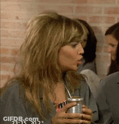 A Woman Is Drinking A Can Of Soda With A Straw And The Time Is 2:35 GIF