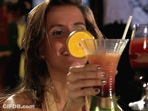 A Woman Is Drinking A Cocktail With A Straw And A Slice Of Lemon GIF