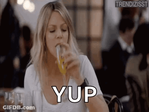 A Woman Is Drinking A Glass Of Orange Juice In A Restaurant And Saying Yup . GIF