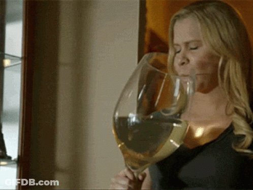 A Woman Is Drinking From A Very Large Glass Of Wine GIF