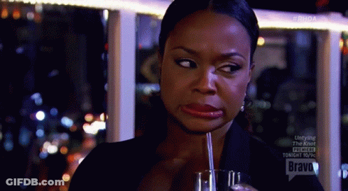 A Woman Is Drinking Through A Straw From A Glass And Making A Funny Face . GIF