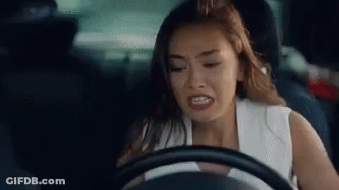A Woman Is Driving A Car And Making A Face . GIF