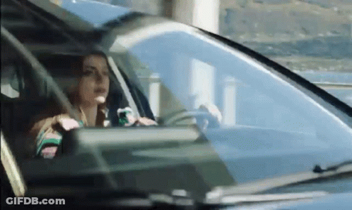 A Woman Is Driving A Car On A Highway . GIF