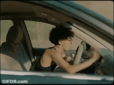A Woman Is Driving A Car Without A Shirt On While Looking Out The Window . GIF