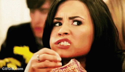 A Woman Is Eating A Bag Of Chips And Making A Face . GIF