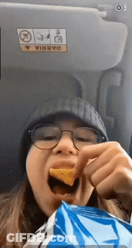 A Woman Is Eating A Bag Of Chips In A Car GIF