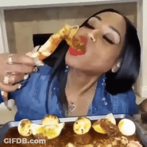 A Woman Is Eating A Crab Leg With A Spoon . GIF