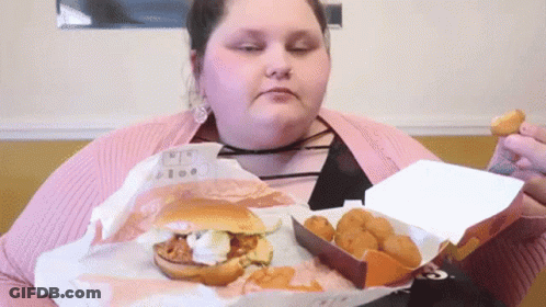 A Woman Is Eating A Hamburger And Chicken Nuggets From A Box GIF
