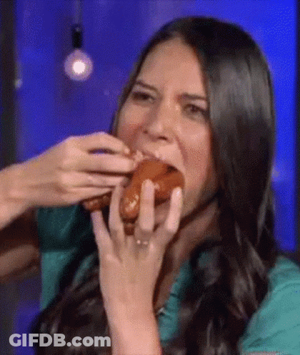 A Woman Is Eating A Hot Dog With Her Hands While Wearing A Ring . GIF
