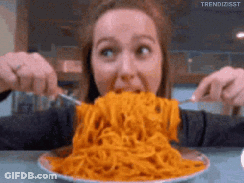 A Woman Is Eating A Large Bowl Of Spaghetti With A Fork And Knife GIF